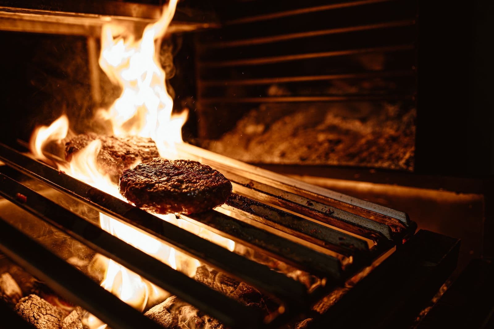 Burger patty searing over open flame