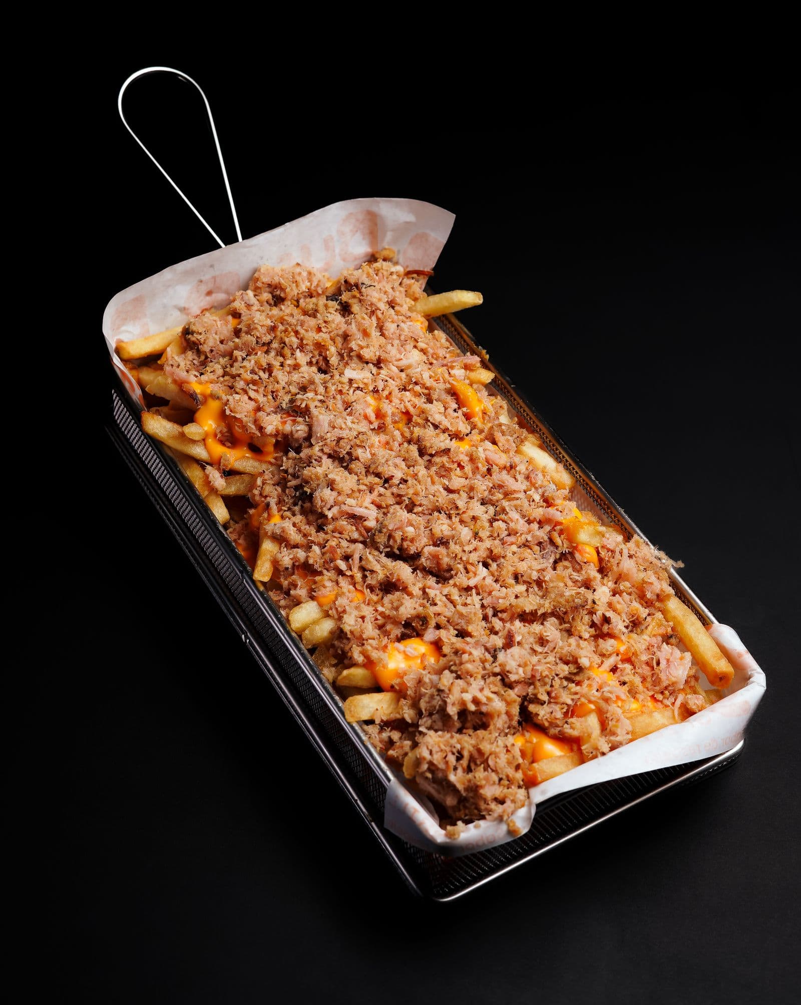 Fry basket loaded with jerk chicken and cheese sauce