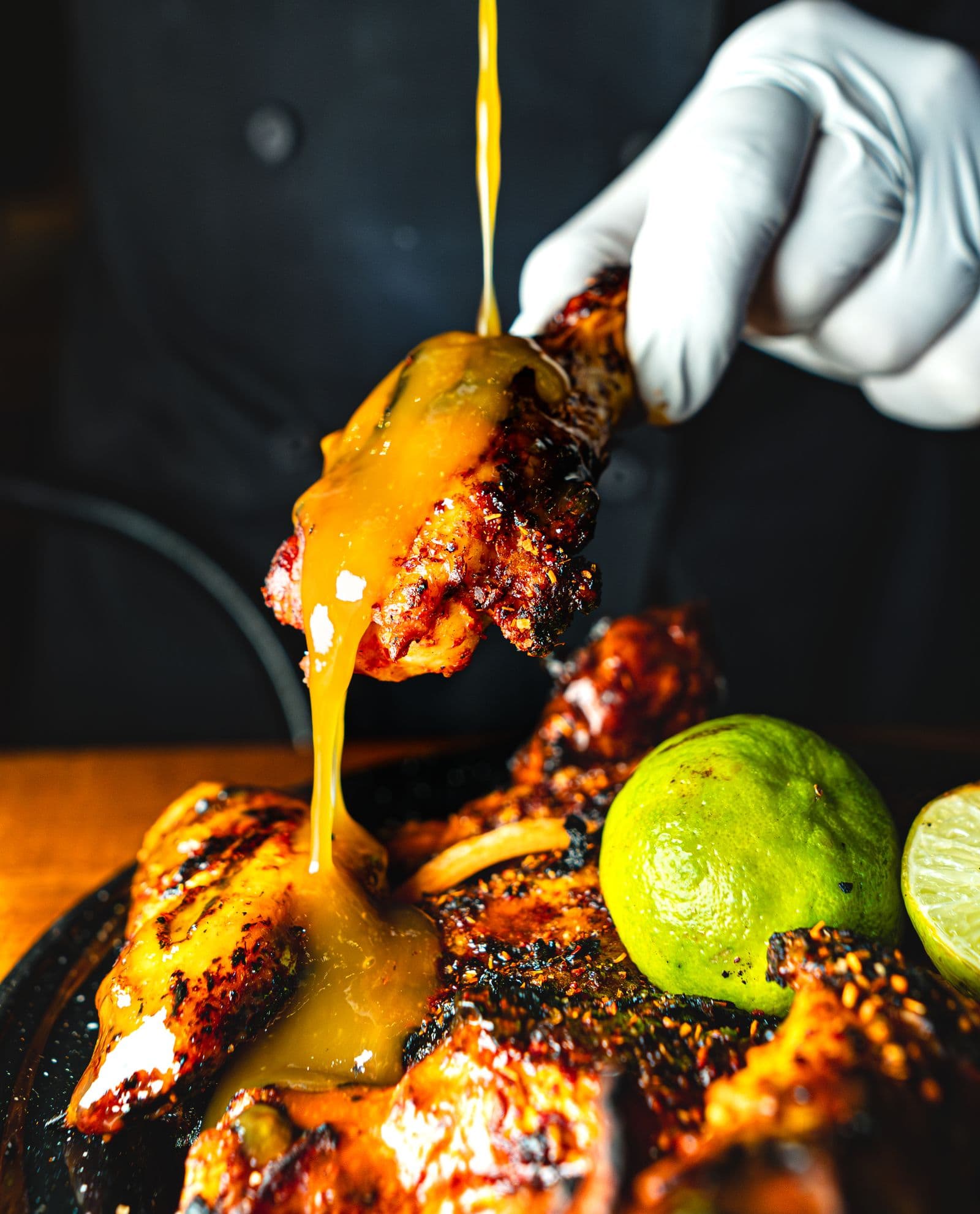 Golden house sauce cascading over charred jerk chicken