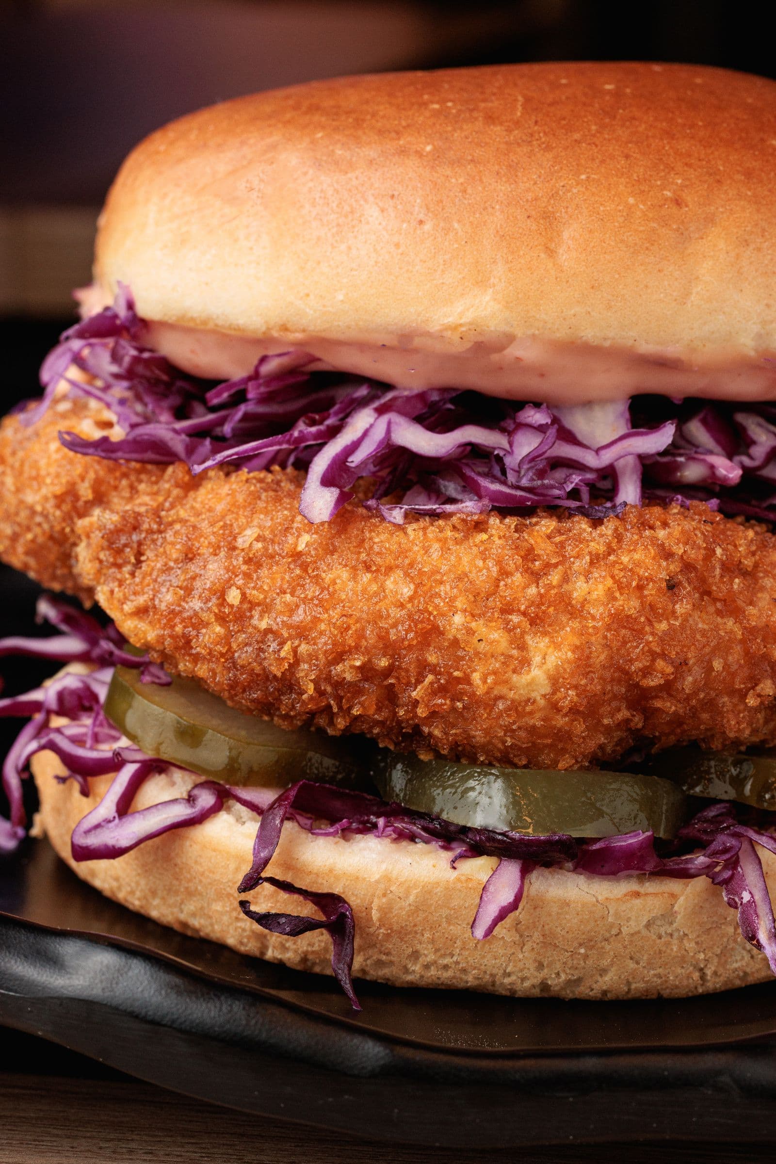 Crispy fried chicken sandwich with slaw and pickles up close